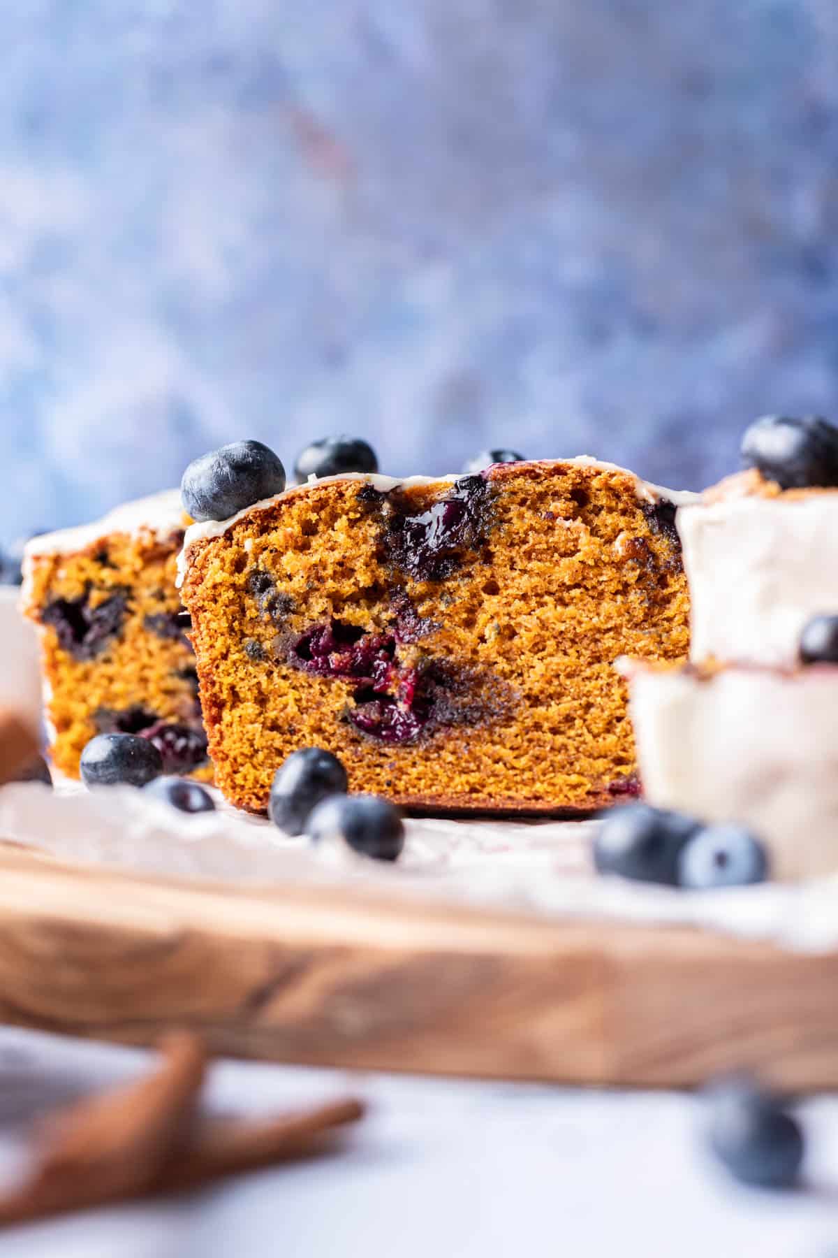 The inside of a loaf of pumpkin blueberry bread with fresh blueberries.