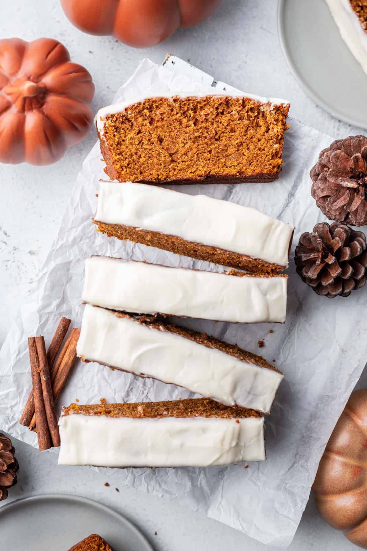Pumpkin bread with cream cheese frosting sliced into pieces for serving.