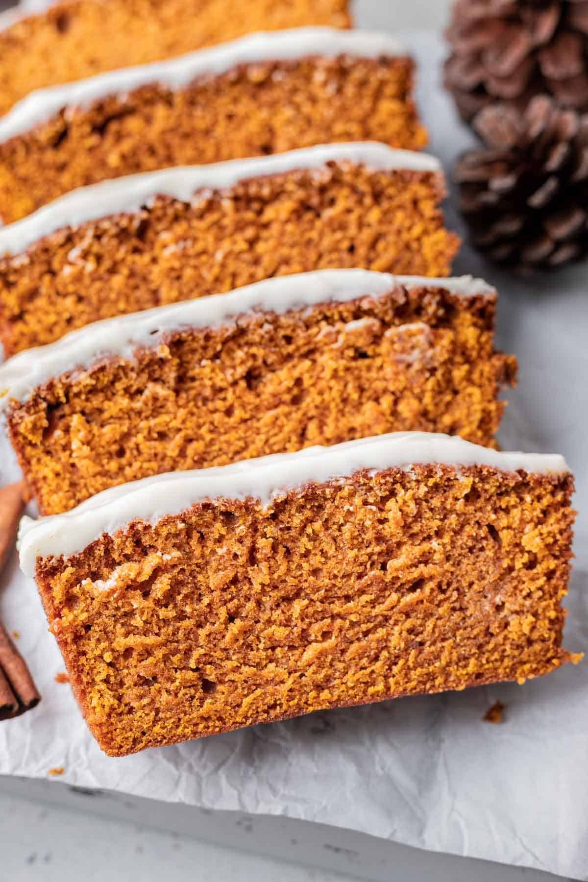 Sliced pumpkin bread with cream cheese frosting on a serving tray.