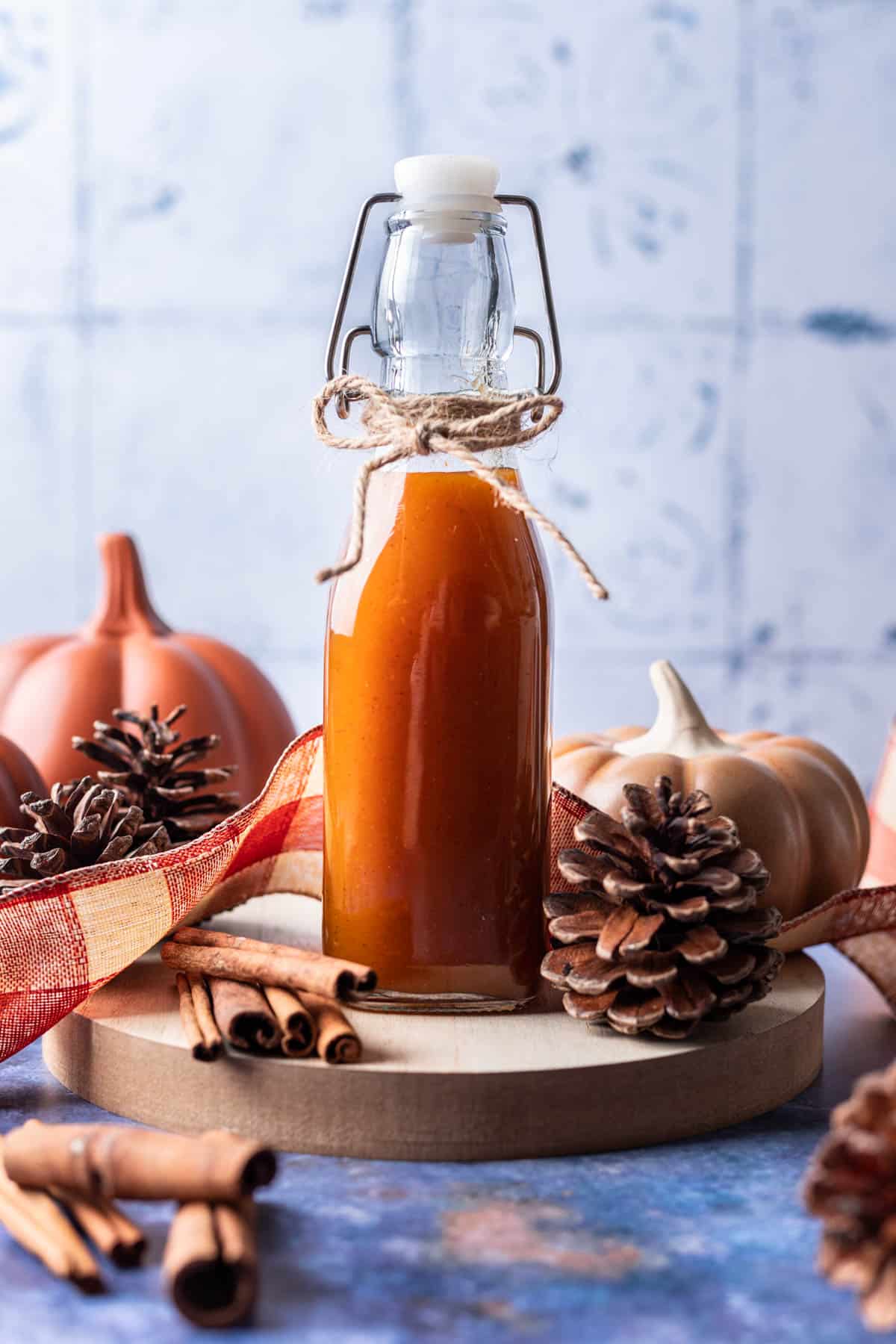 Pumpkin spice simple syrup in a bottle on a serving tray.