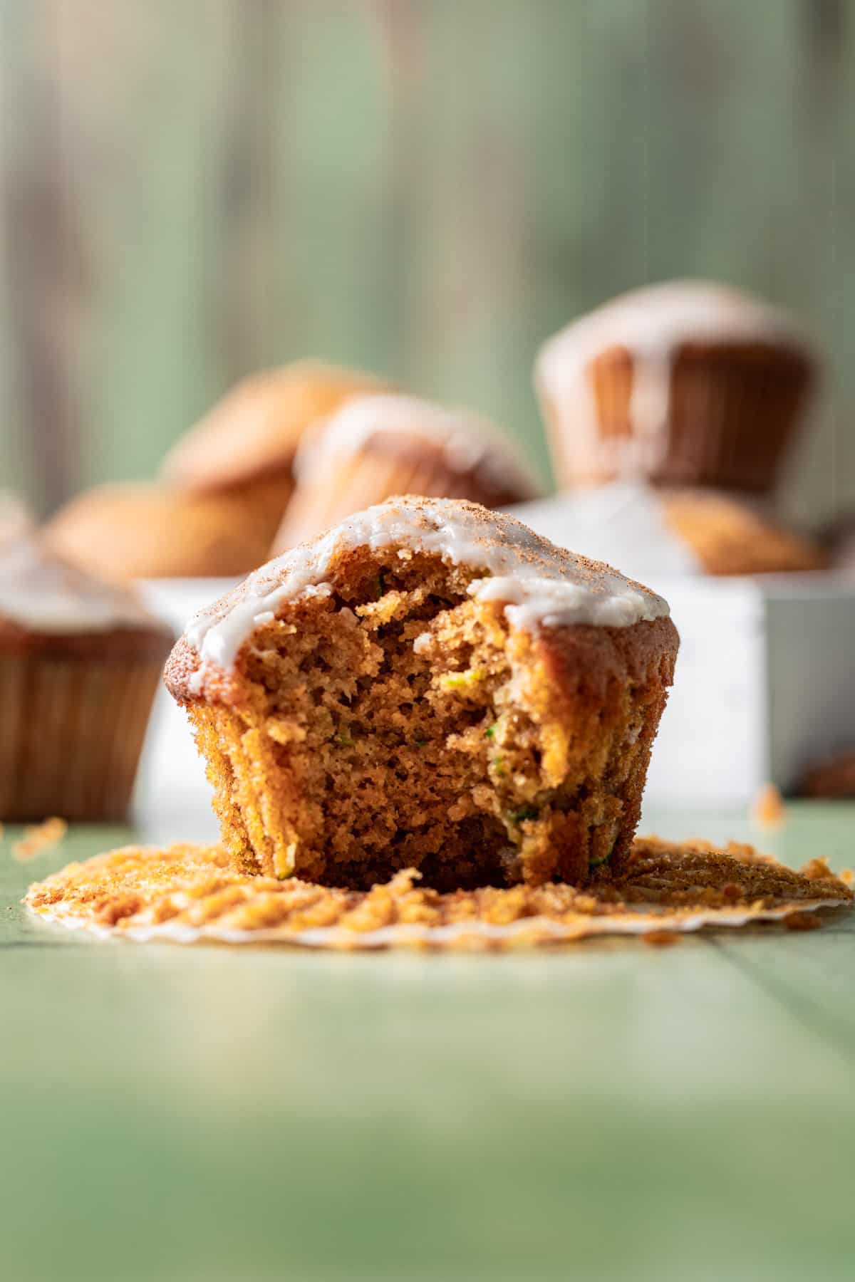 A pumpkin zucchini muffin with a bite taken out to show the fluffy middle.