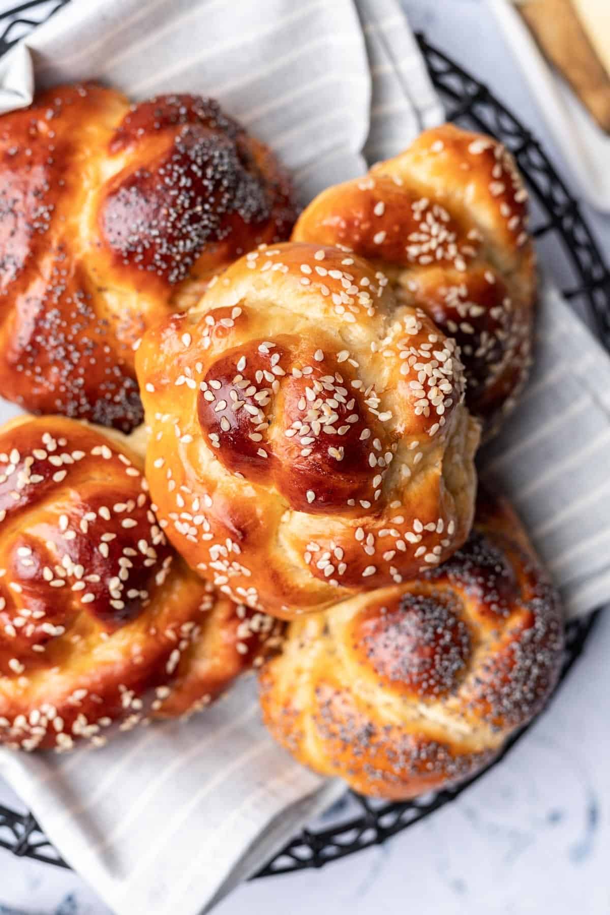 Challah rolls topped with sesame and poppy seeds in a bread basket.