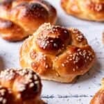 Challah rolls topped with sesame seeds on a tile backdrop.