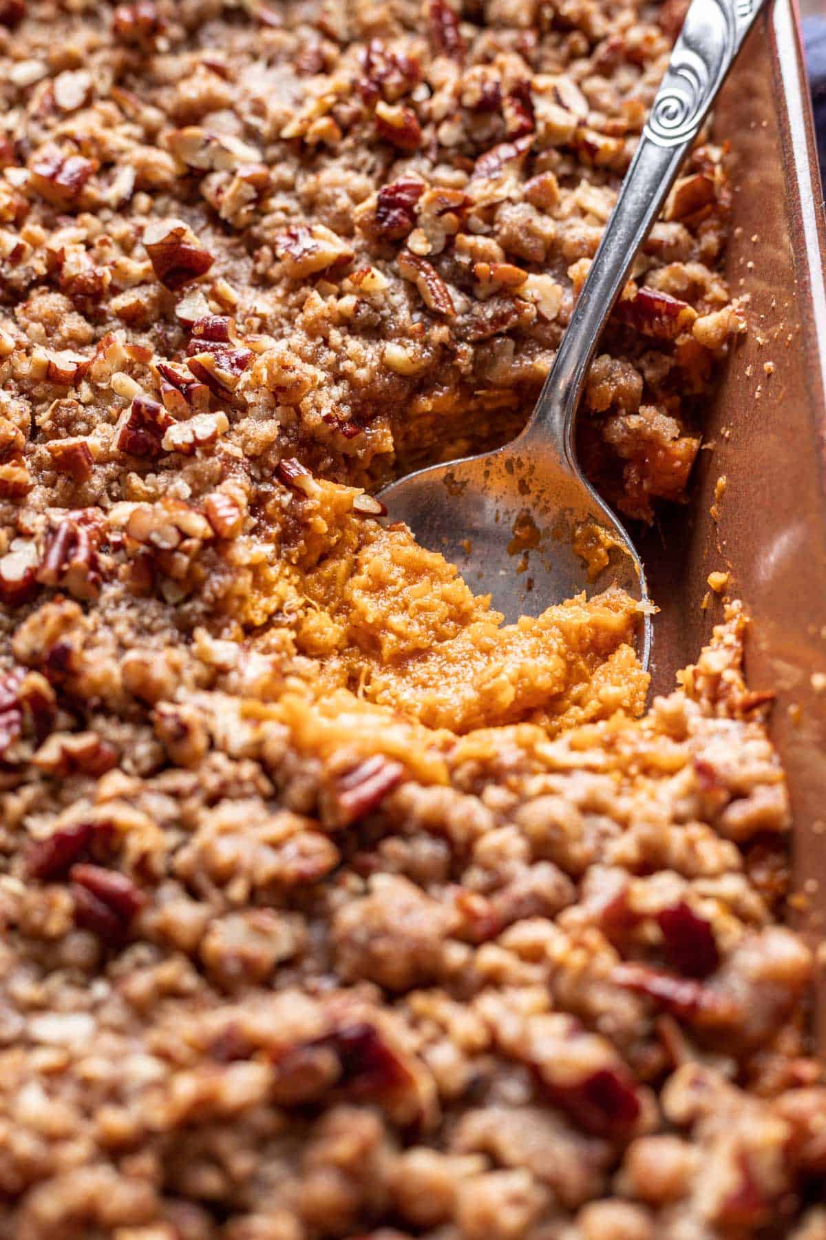 Sweet potato crunch casserole scooped with a spoon to show the creamy sweet potatoes and the crispy crunch topping.