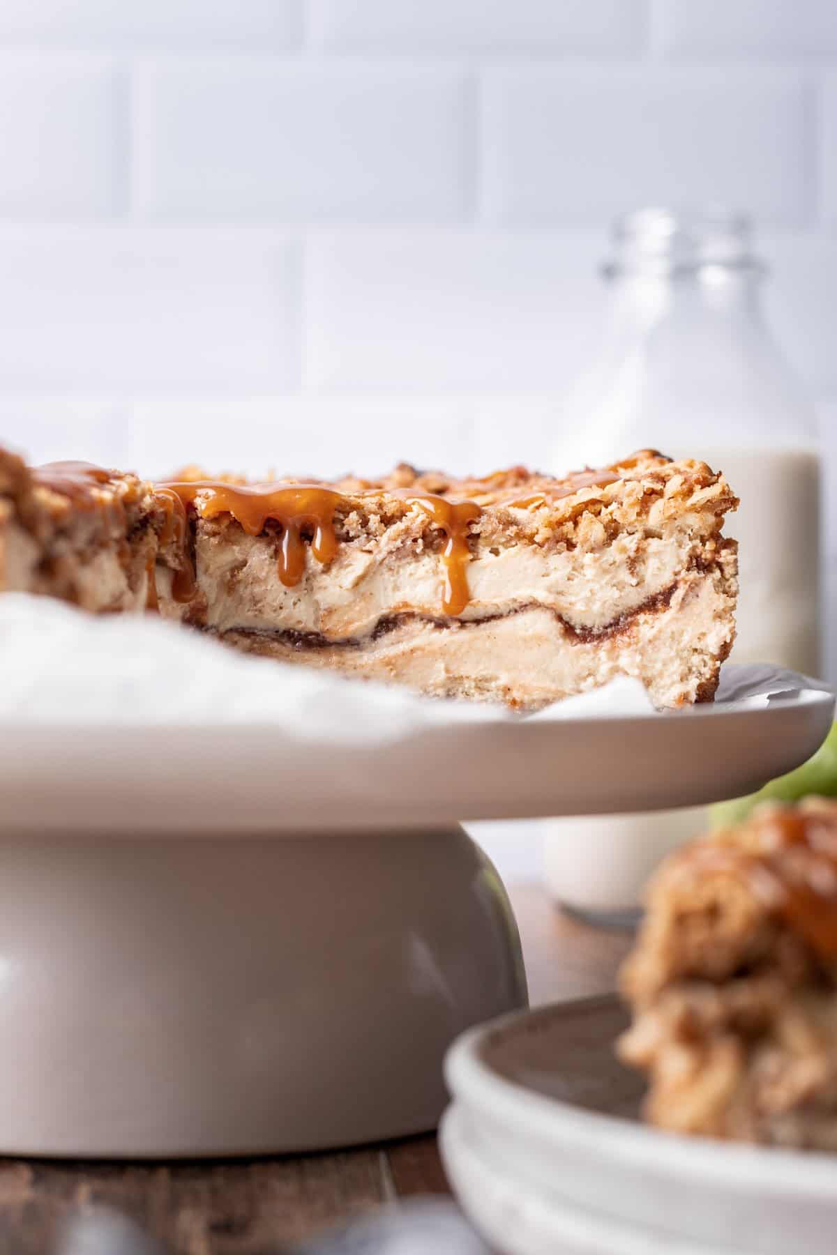 Apple crumble cheesecake on a cake dish with an apple butter swirl in the middle.