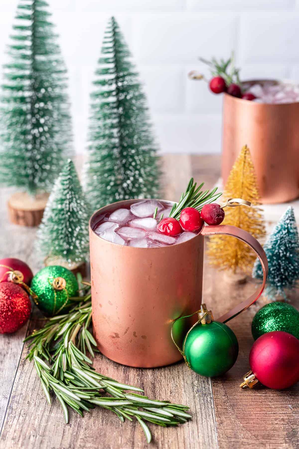 Christmas moscow mule in a copper mug garnished with fresh rosemary and cranberries.