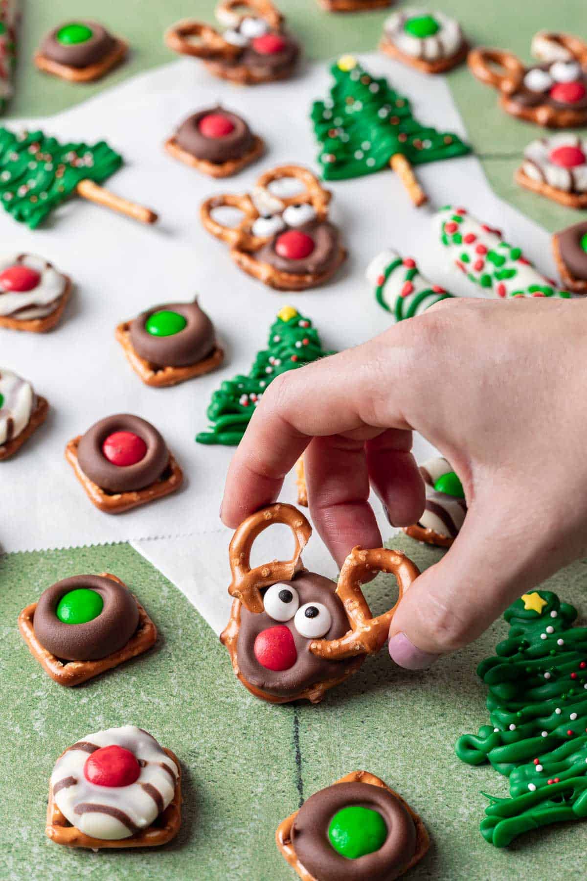 A hand picking up a reindeer pretzel to snack on.