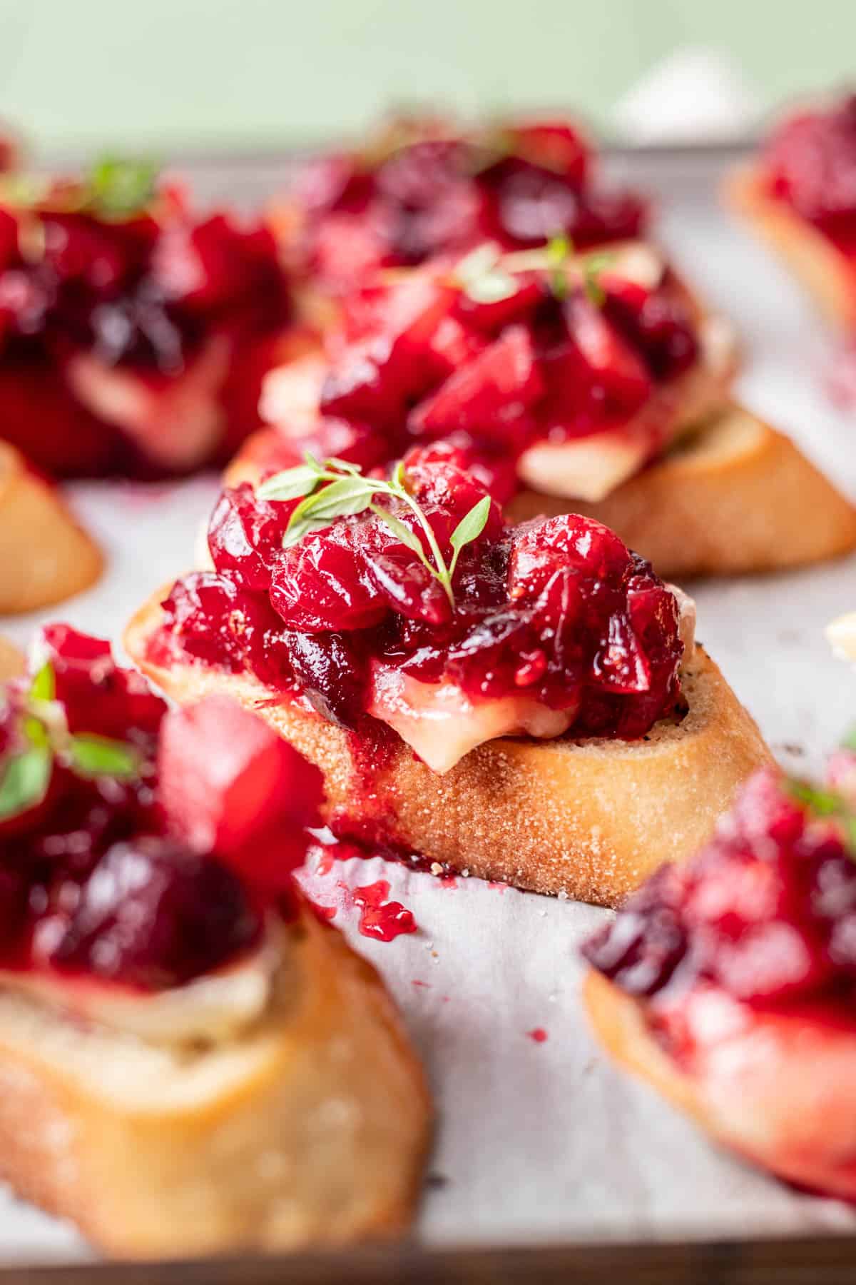 Cranberry brie crostini on a serving platter garnished with fresh thyme.