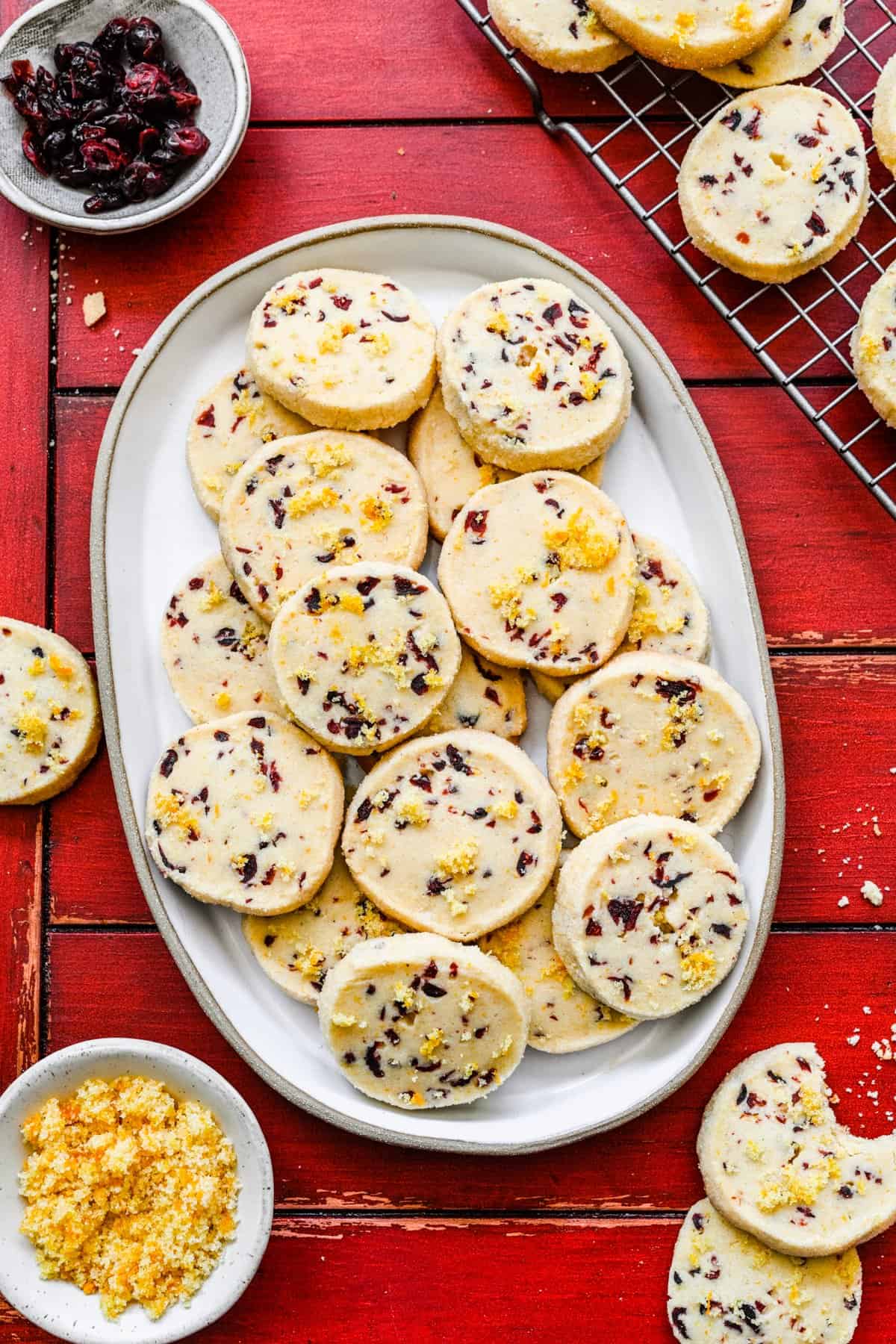 Cranberry orange shortbread cookies on a plate with broken cookies around it.