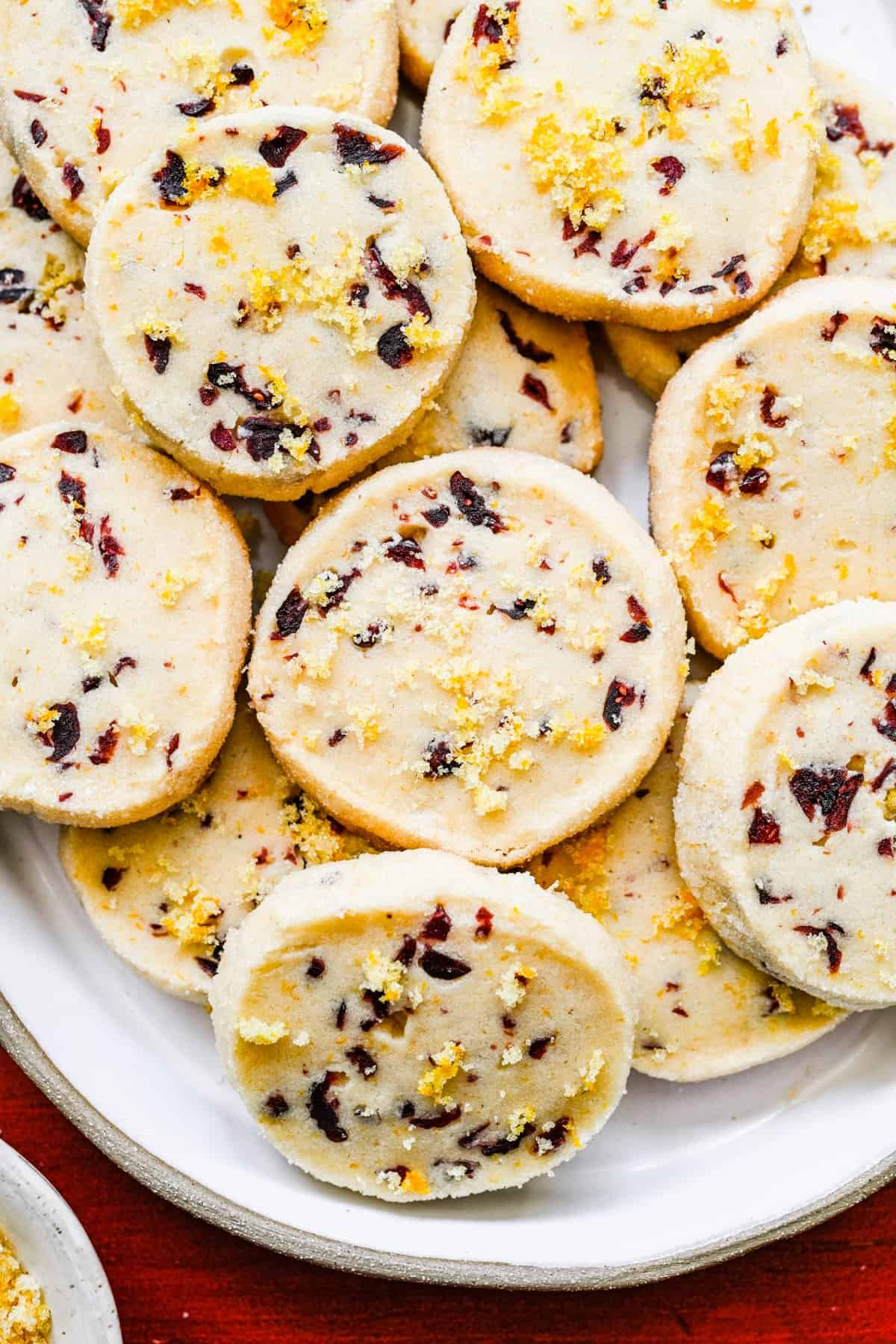 Cranberry orange shortbread cookies stacked on top of each other on a serving plate.
