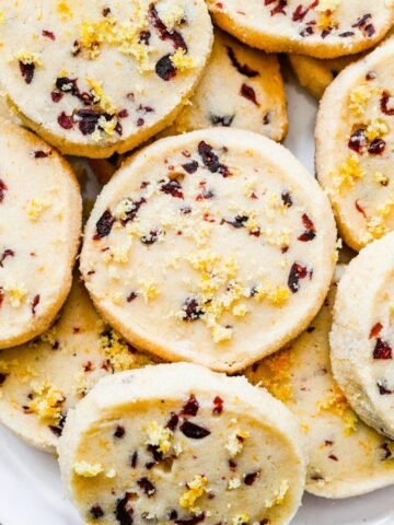 Cranberry orange shortbread cookies stacked on a plate.