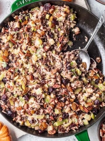 Thanksgiving wild rice in a skillet with a serving spoon.