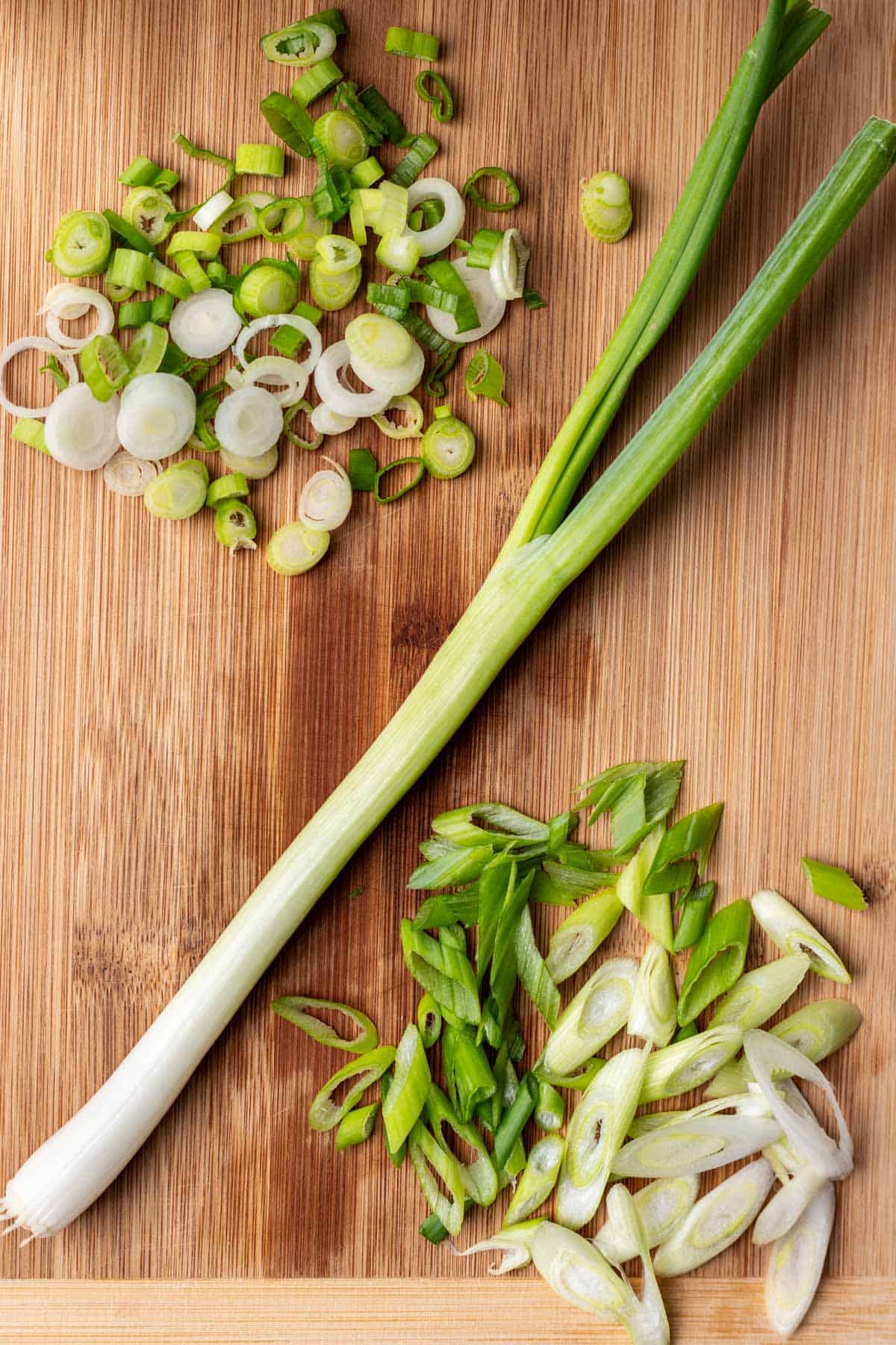 A whole green onion, sliced green onion, and green onion cut on a bias.