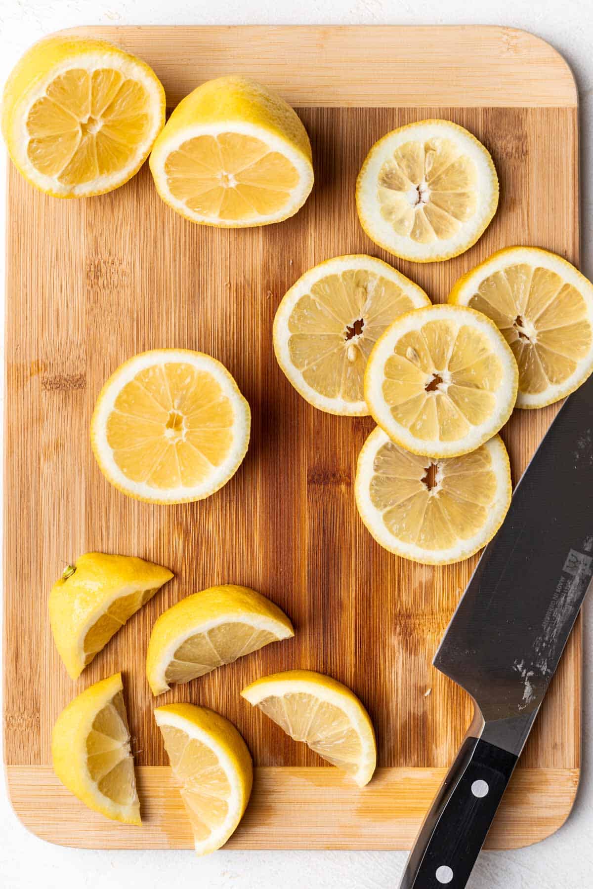 Lemon slices and wedges on a wood cutting board.