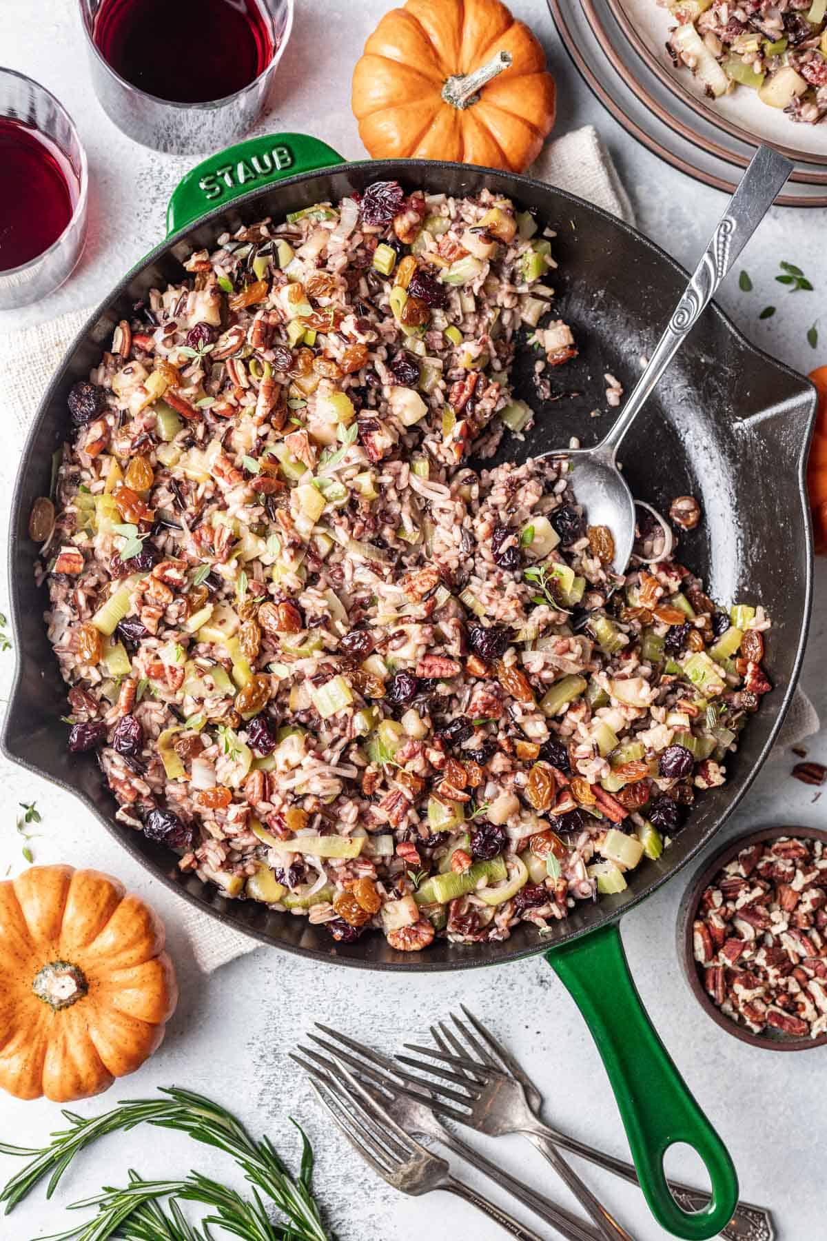 Wild rice for Thanksgiving in a green skillet with a serving spoon.