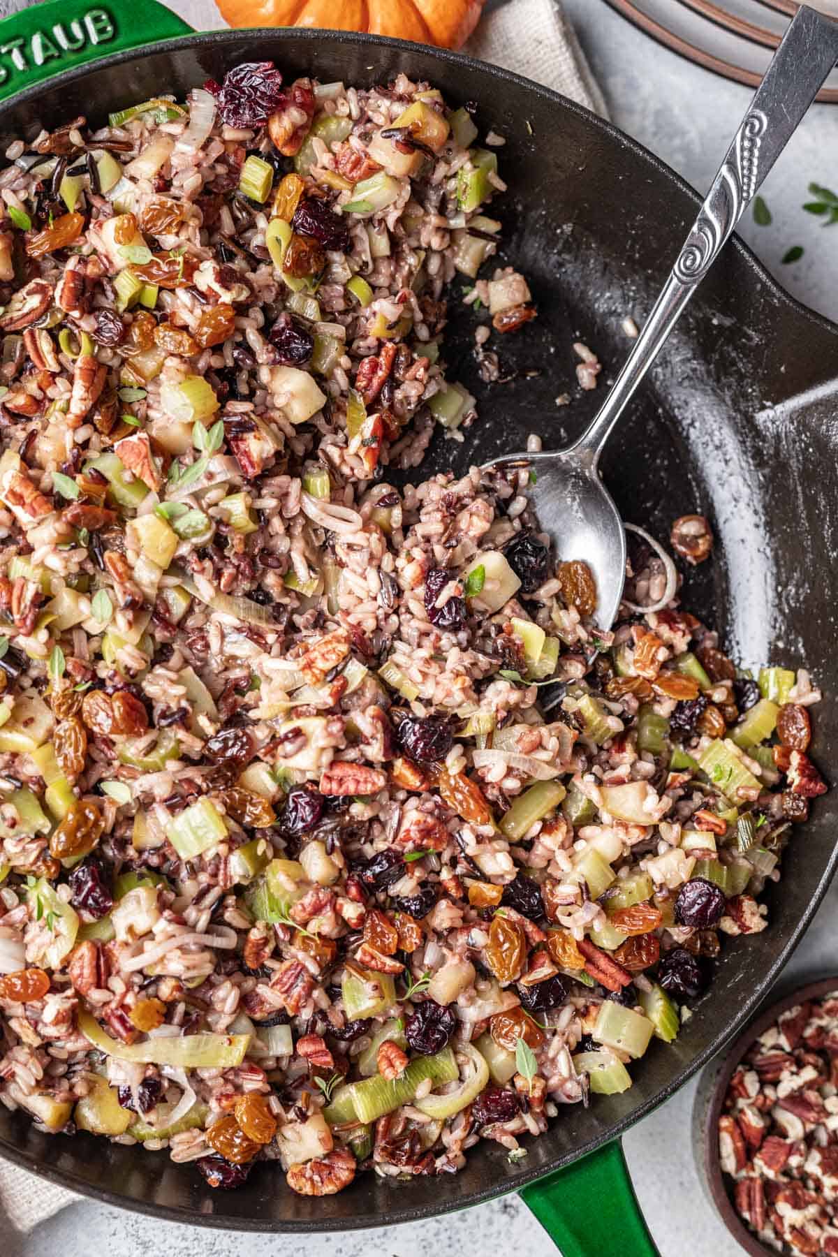 Wild rice for thanksgiving in a skillet topped with dried cranberries and pecans.