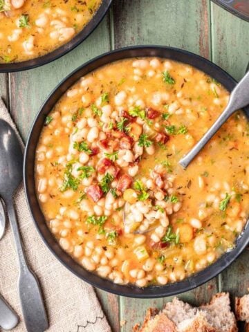 Instant pot navy bean soup in a bowl with a spoon.
