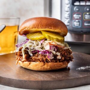 Shredded instant pot pork butt on a bun with slaw and pickles.