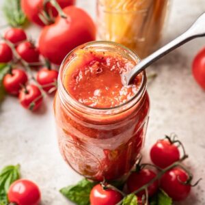 Instant pot tomato sauce in a glass jar with a spoon.