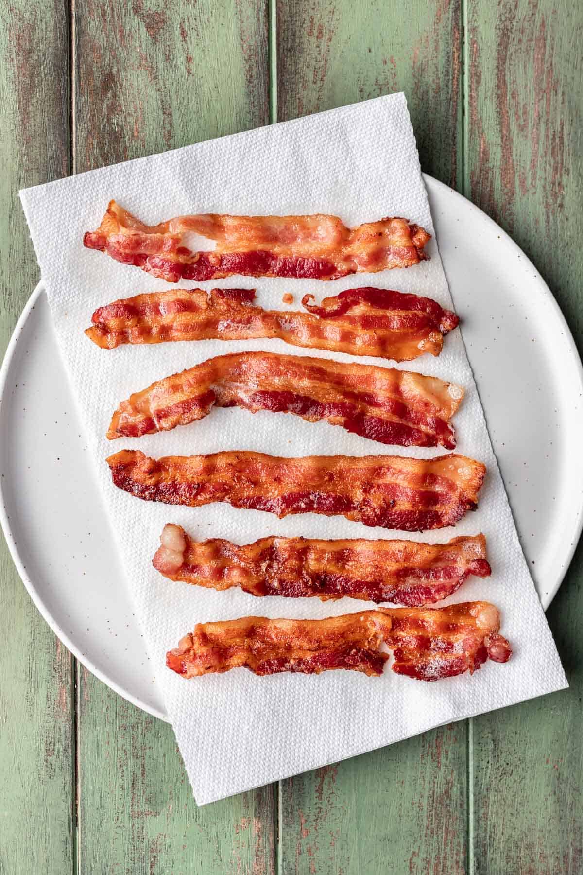 Strips of bacon on a paper towel-lined plate.
