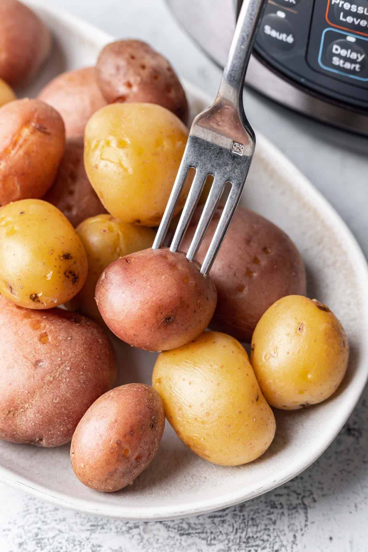 Instant pot boiled potatoes on a serving platter with a fork.