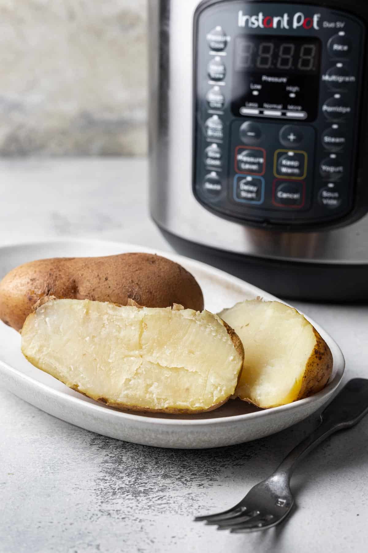 Boiled russet potatoes cut in half on a plate to show the interior.