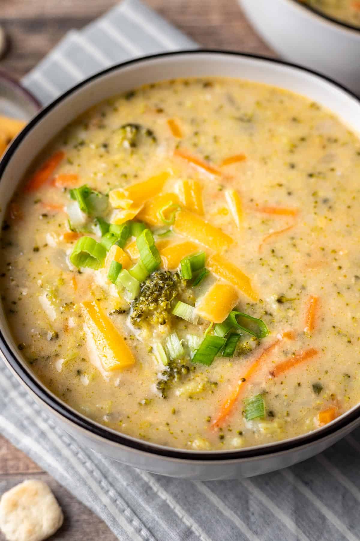 Instant pot broccoli cheddar soup garnished with shredded cheese and green onions.