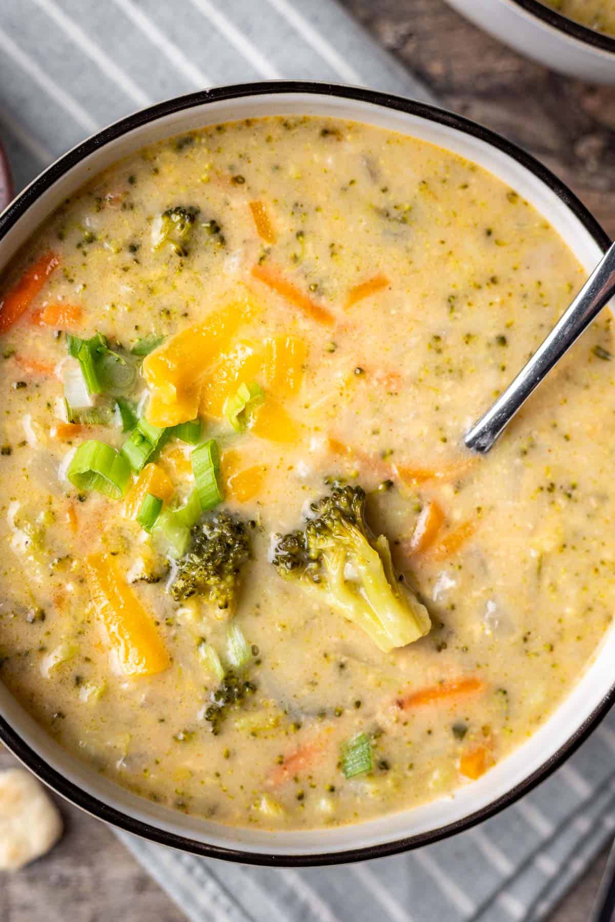 Creamy broccoli cheddar soup in a bowl with a spoon showing a piece of broccoli.
