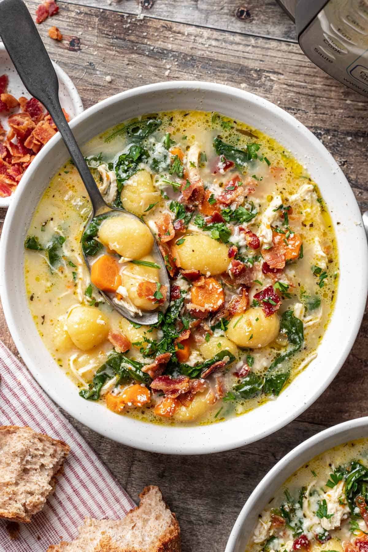 Instant pot chicken gnocchi soup in a white bowl with a spoon.