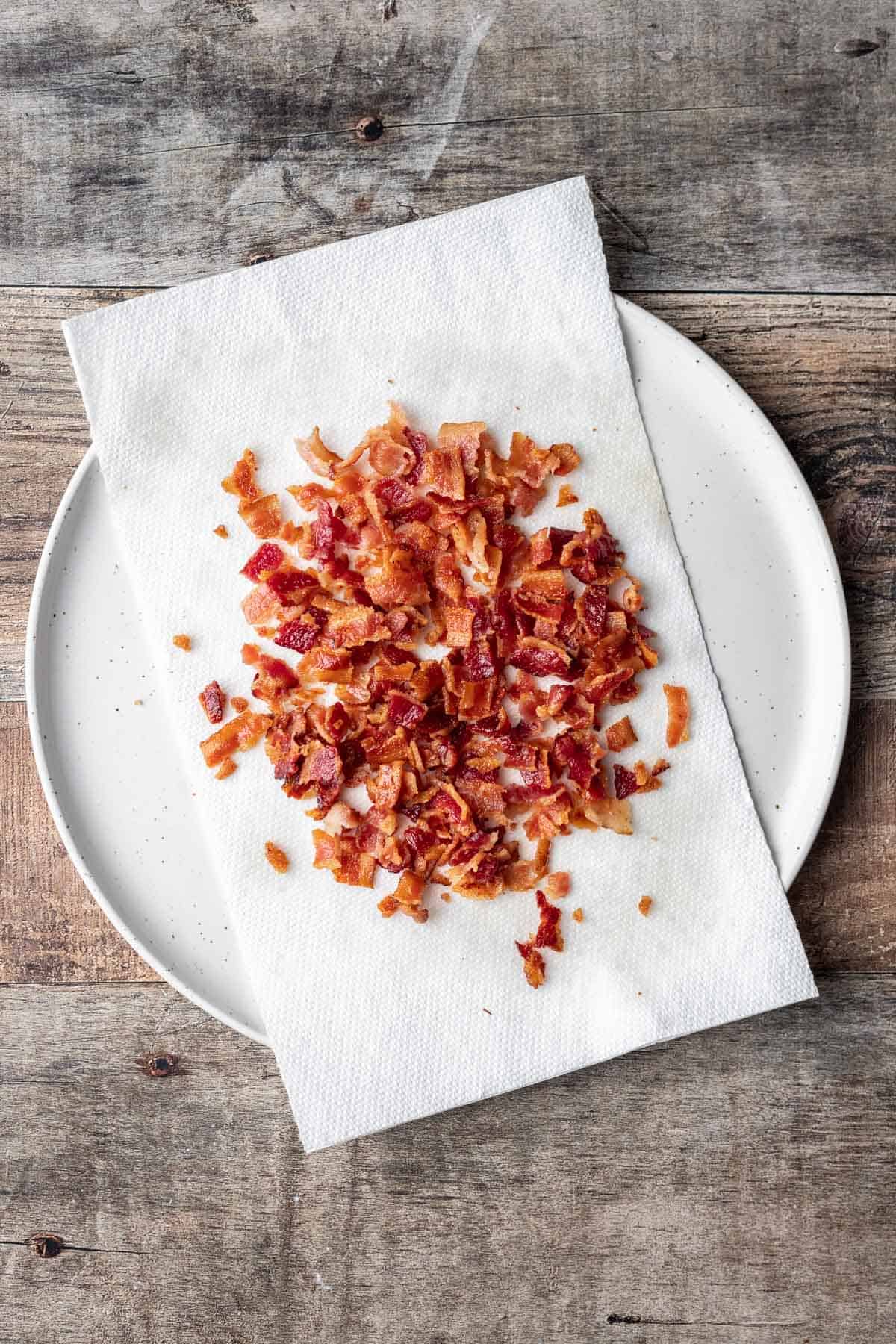 Crumbled bacon on a paper towel lined plate.