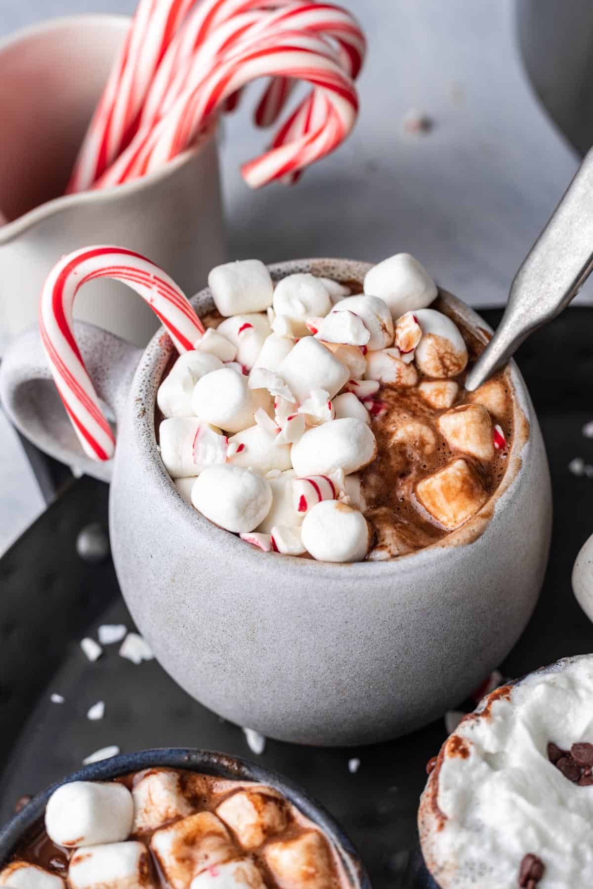 Instant pot hot chocolate in a gray mug with marshmallows and peppermint candies on top.