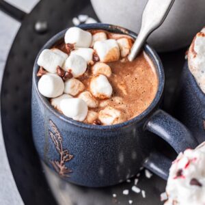Instant pot hot chocolate in a blue mug with marshmallows on top.