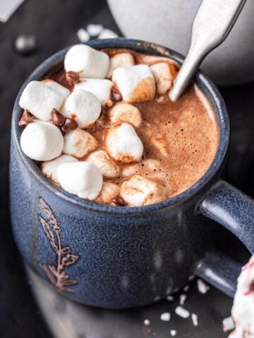 Instant pot hot chocolate in a blue mug with marshmallows on top.