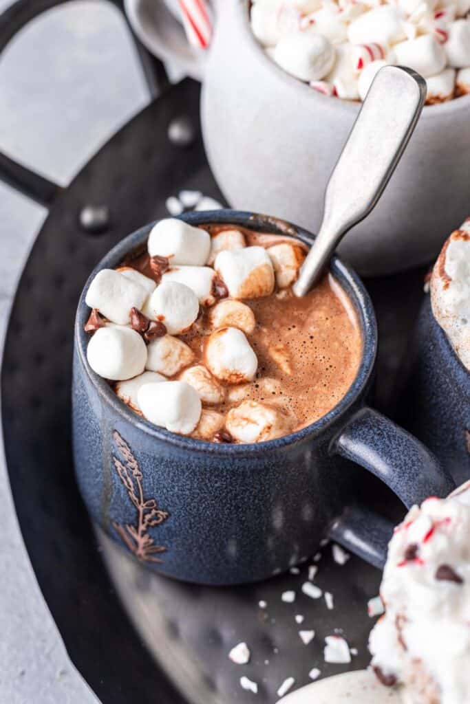 Instant pot hot chocolate in a blue mug with marshmallows on top.