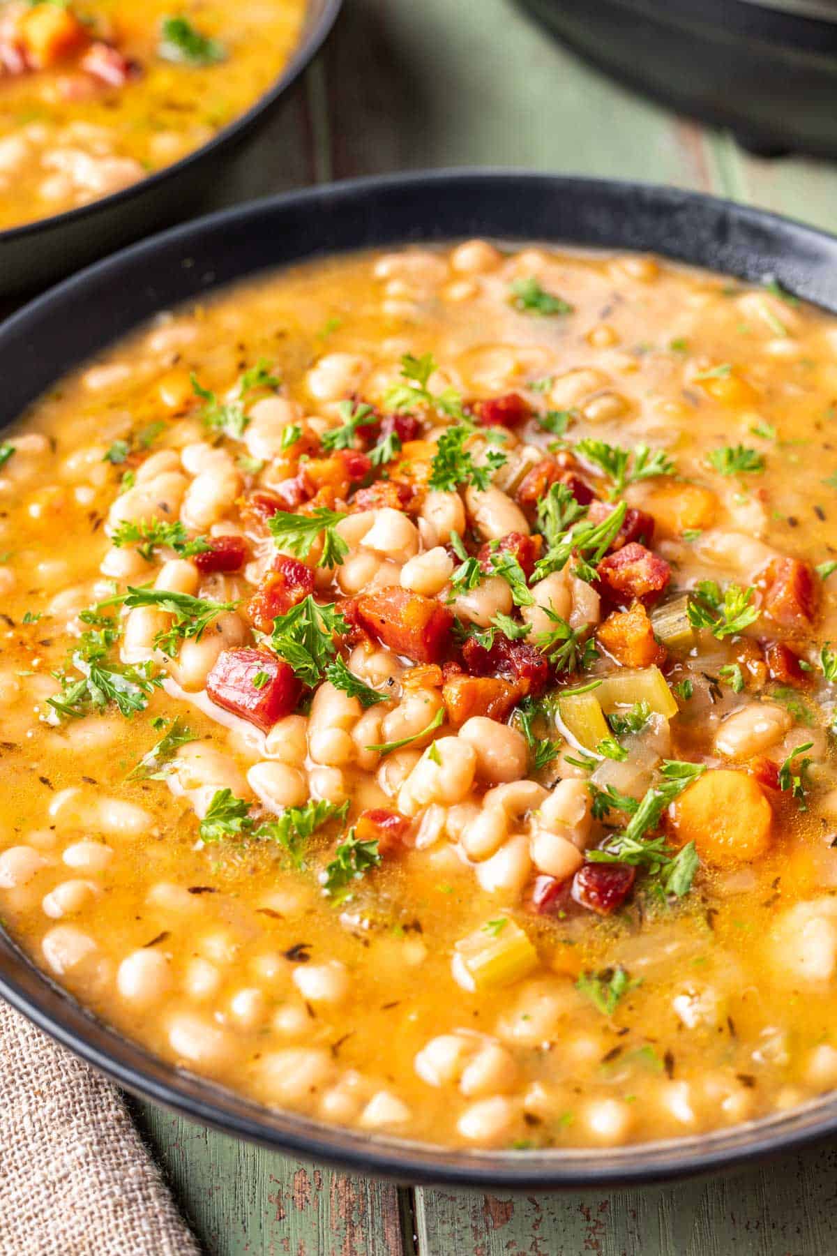 Instant pot navy bean soup in a bowl topped with crispy pancetta.