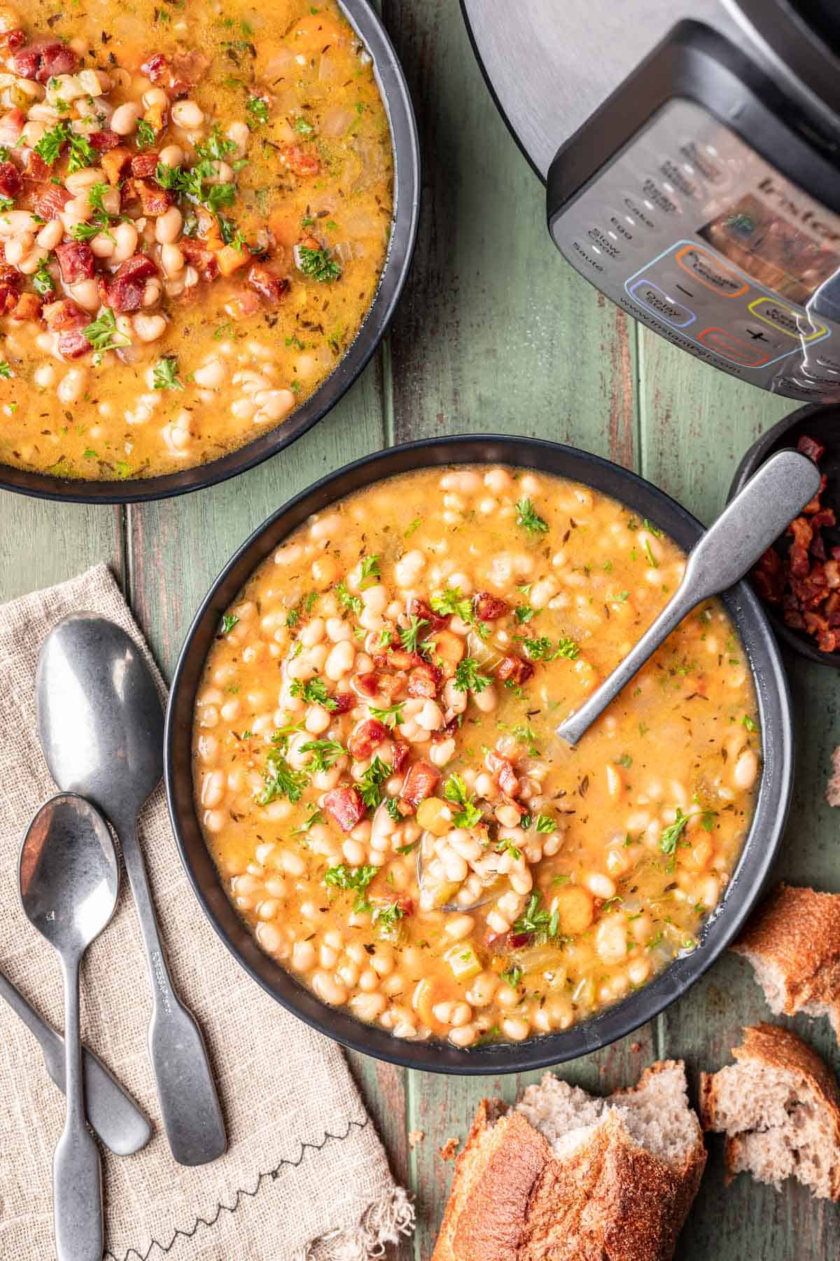 Instant pot navy bean soup in bowls with soup spoons.