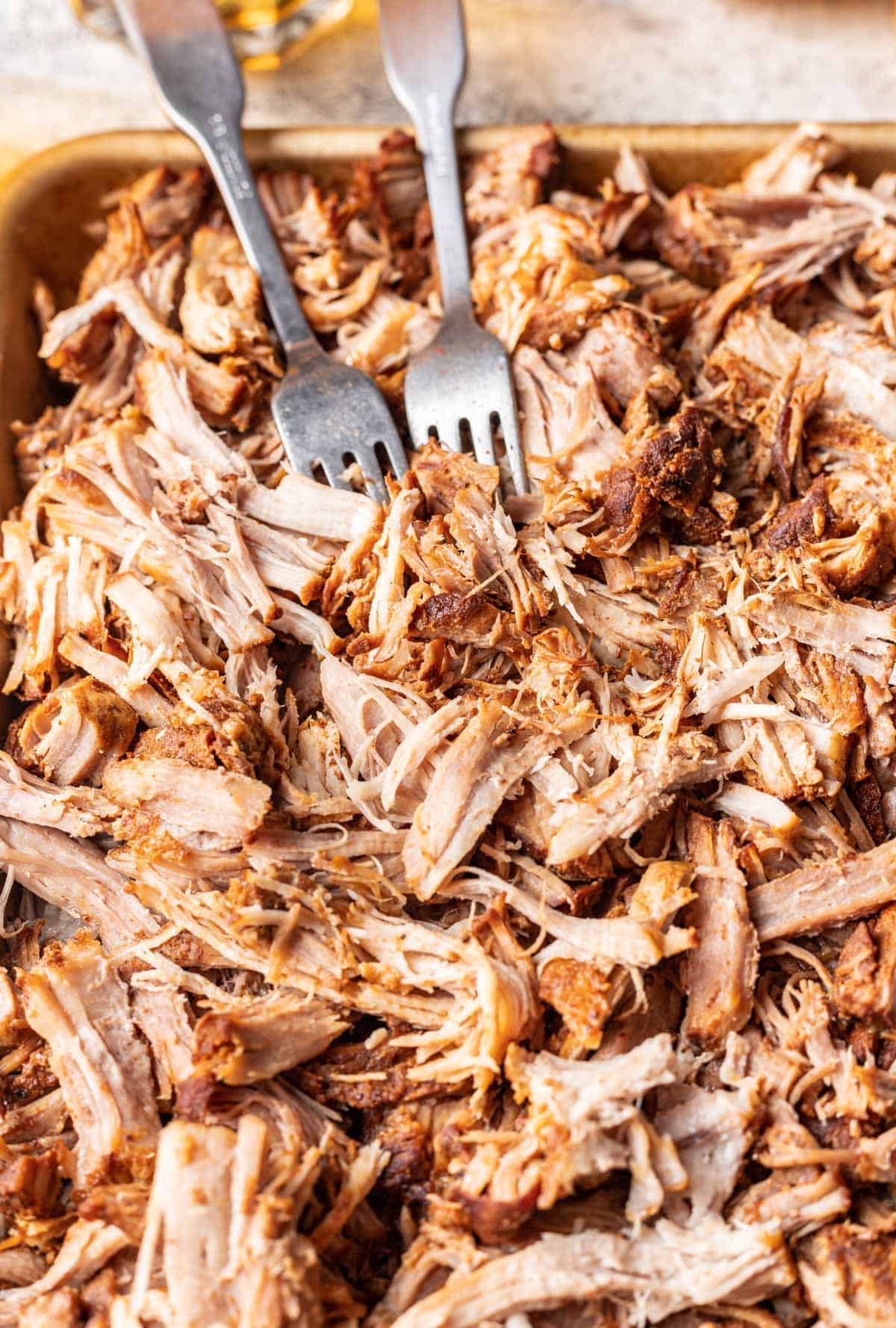 Shredded instant pot pork butt on a tray with 2 forks.