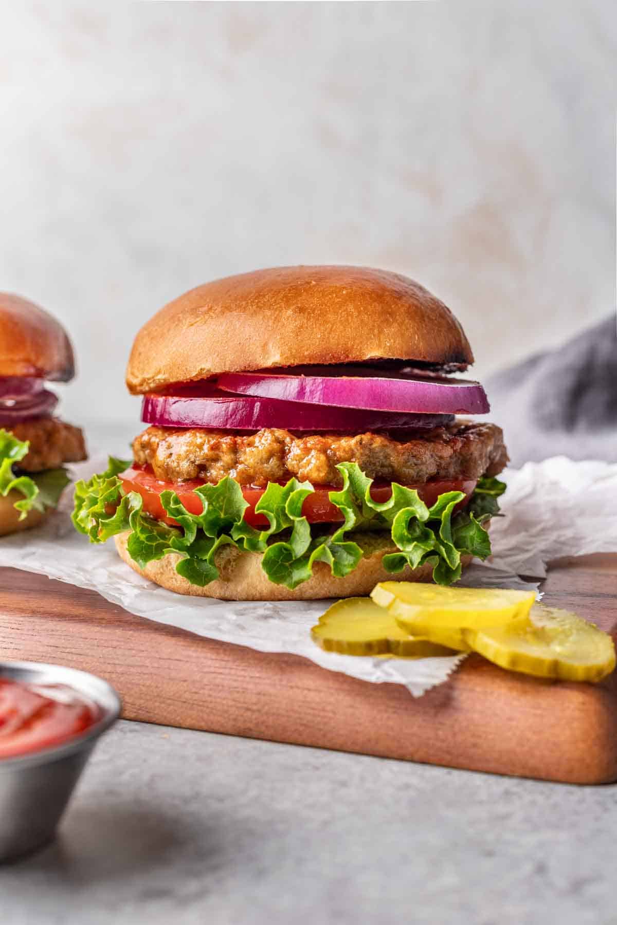 Air fryer turkey burger on a bun with lettuce, tomato, and sliced red onion.