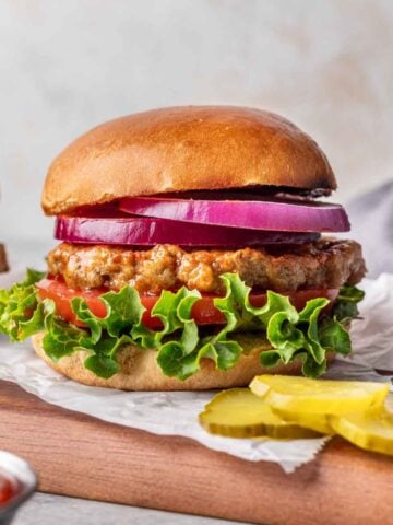 Air fryer turkey burger on a bun with lettuce, tomato, and red onion slices.