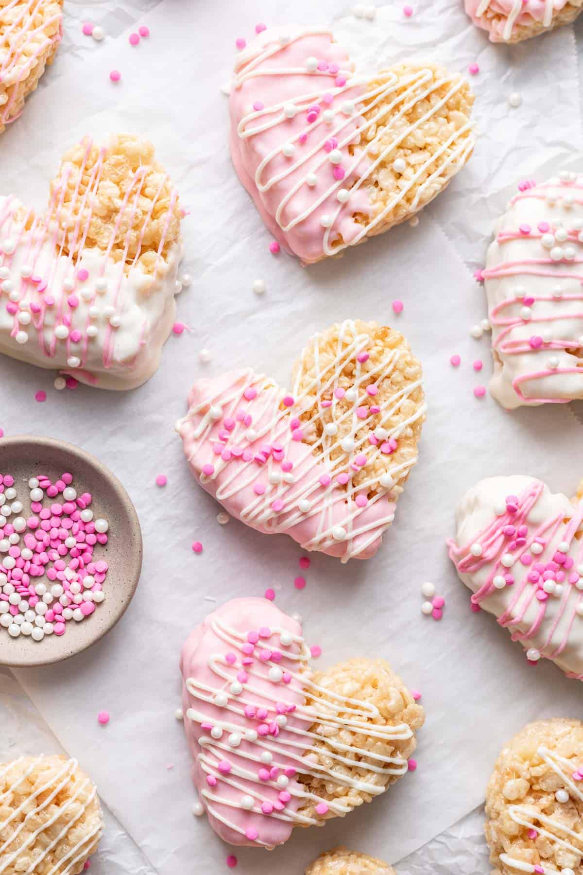 Heart shaped rice krispie treats covered in white chocolate and sprinkles.