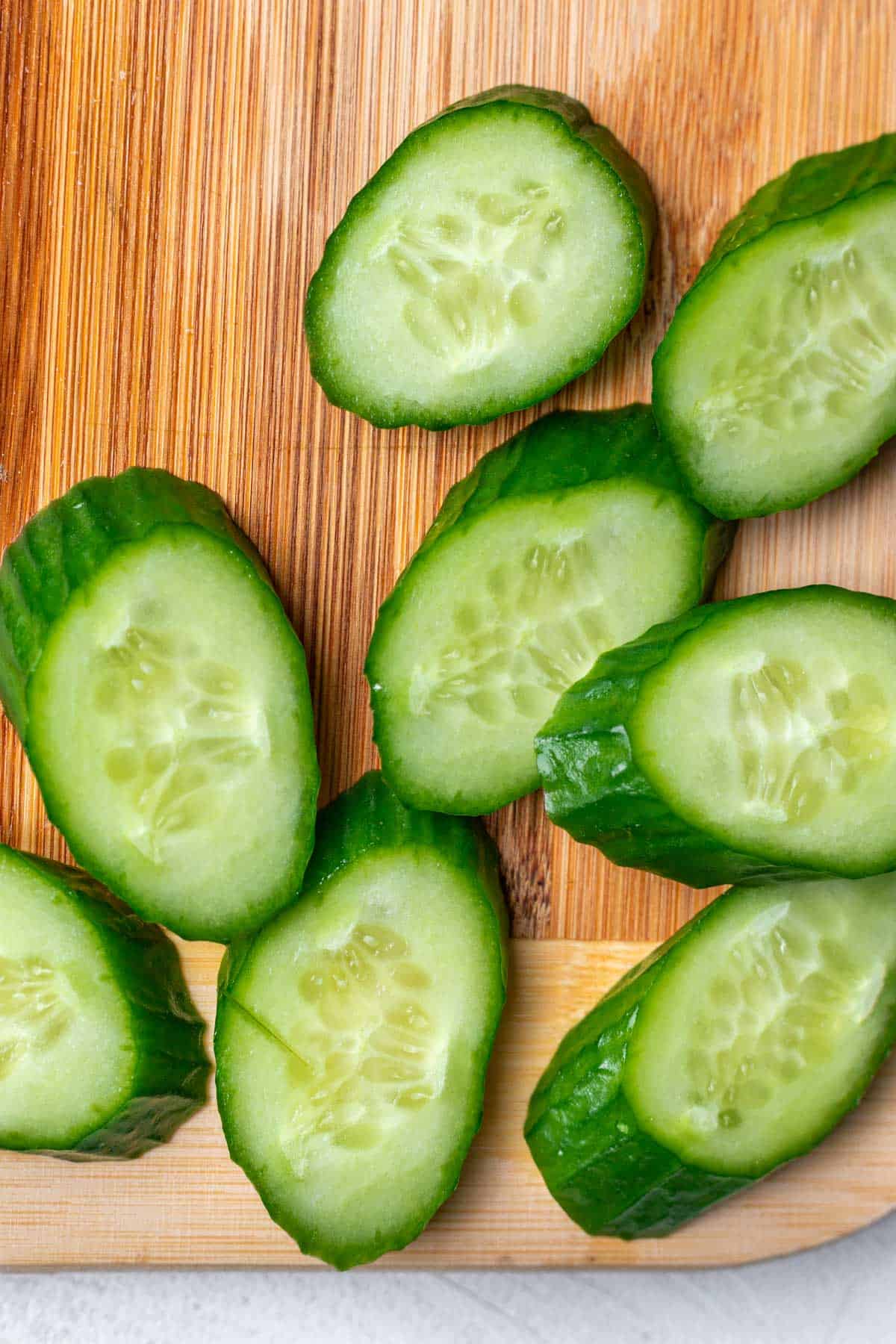 Cucumbers cut on a bias on a cutting board.