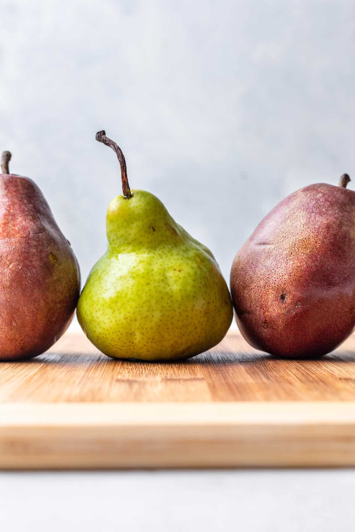 3 pears on a wood cutting board.