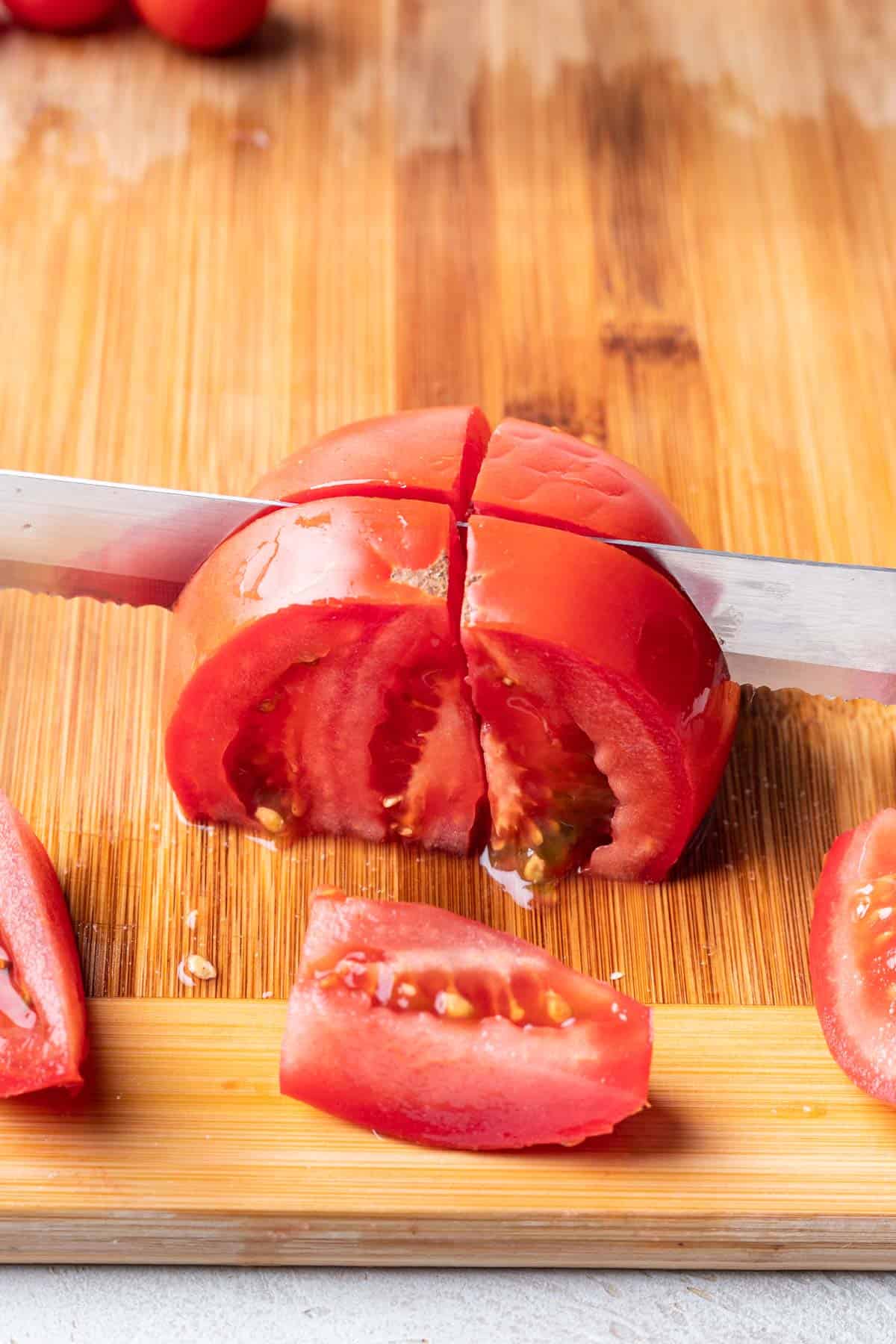 A chef's knife cutting a tomato into wedges.