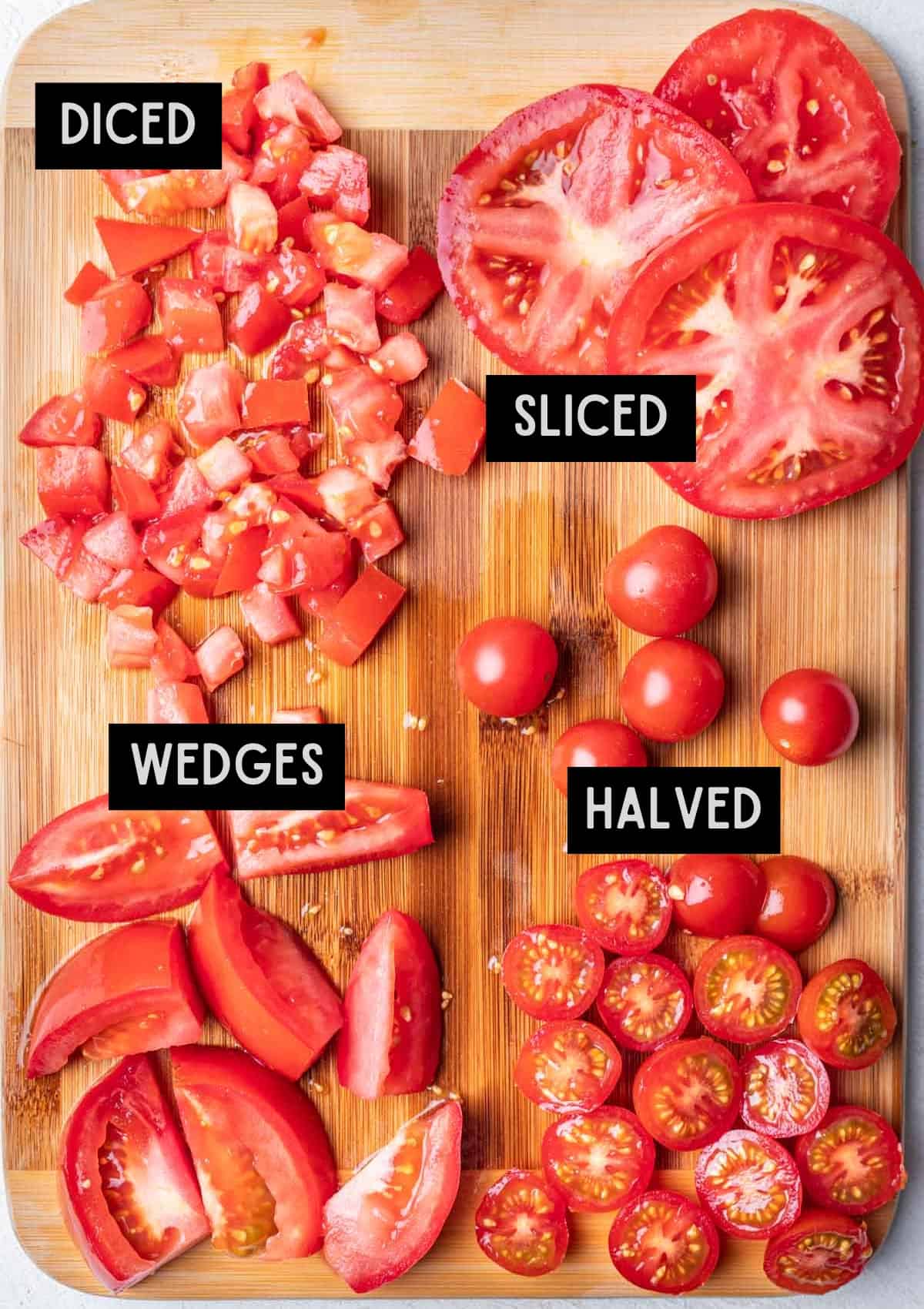Different cuts of tomatoes on a wood cutting board.