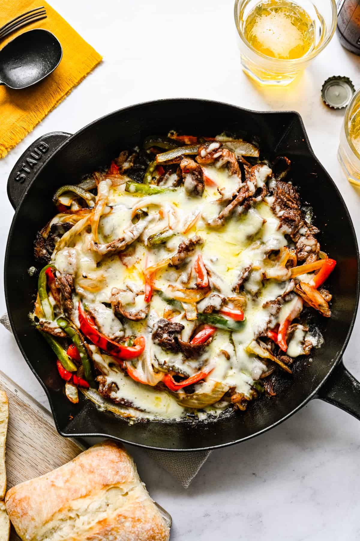 Philly cheesesteak cooked with peppers and onions in a skillet.