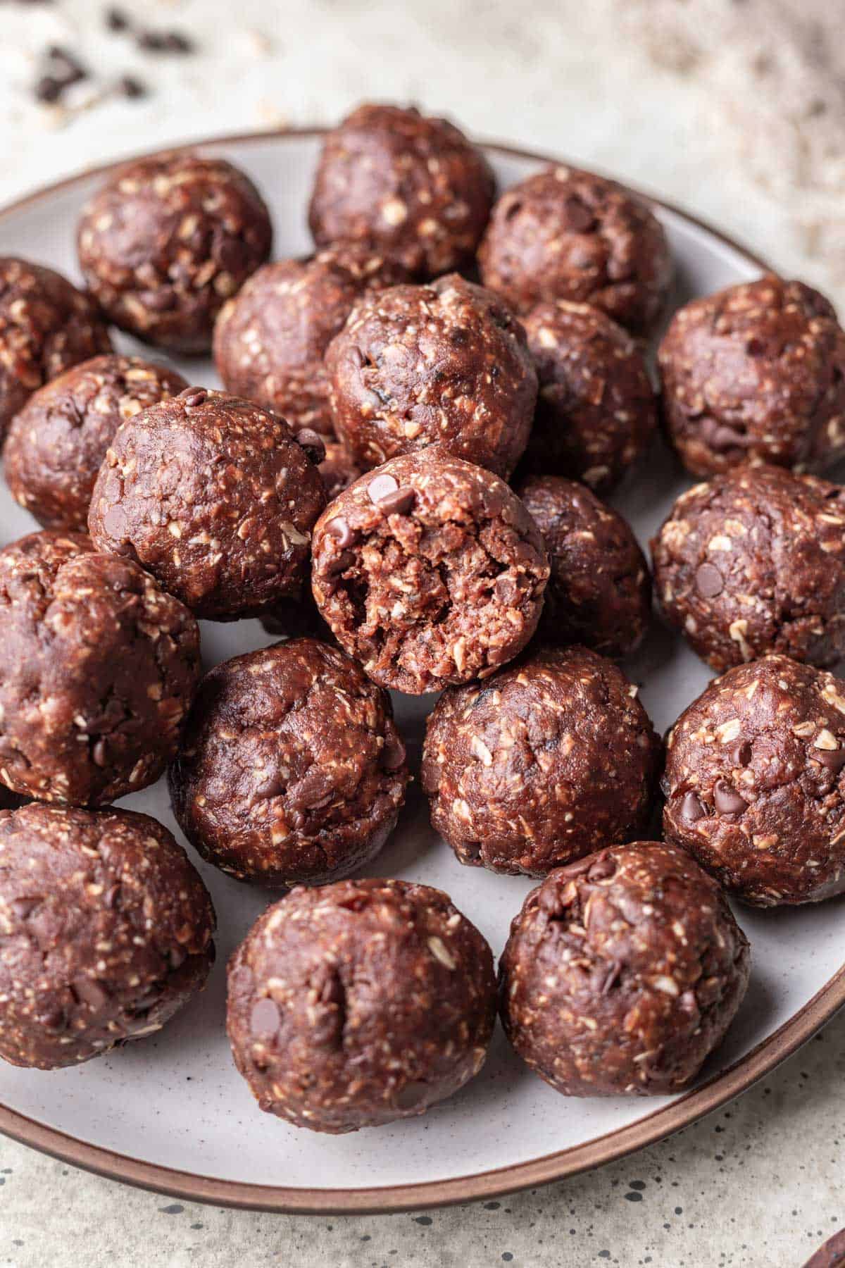 Chocolate date balls on a plate with a bite taken out of one.