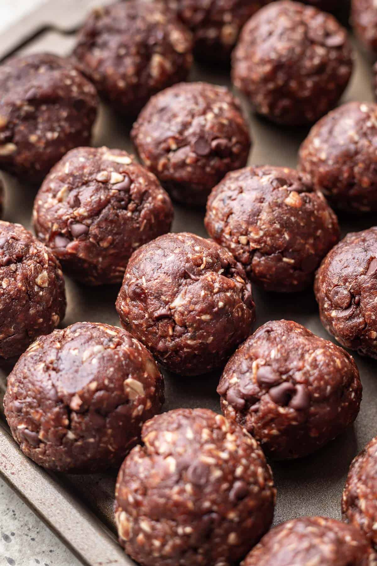 Rolled date balls on a sheet pan.