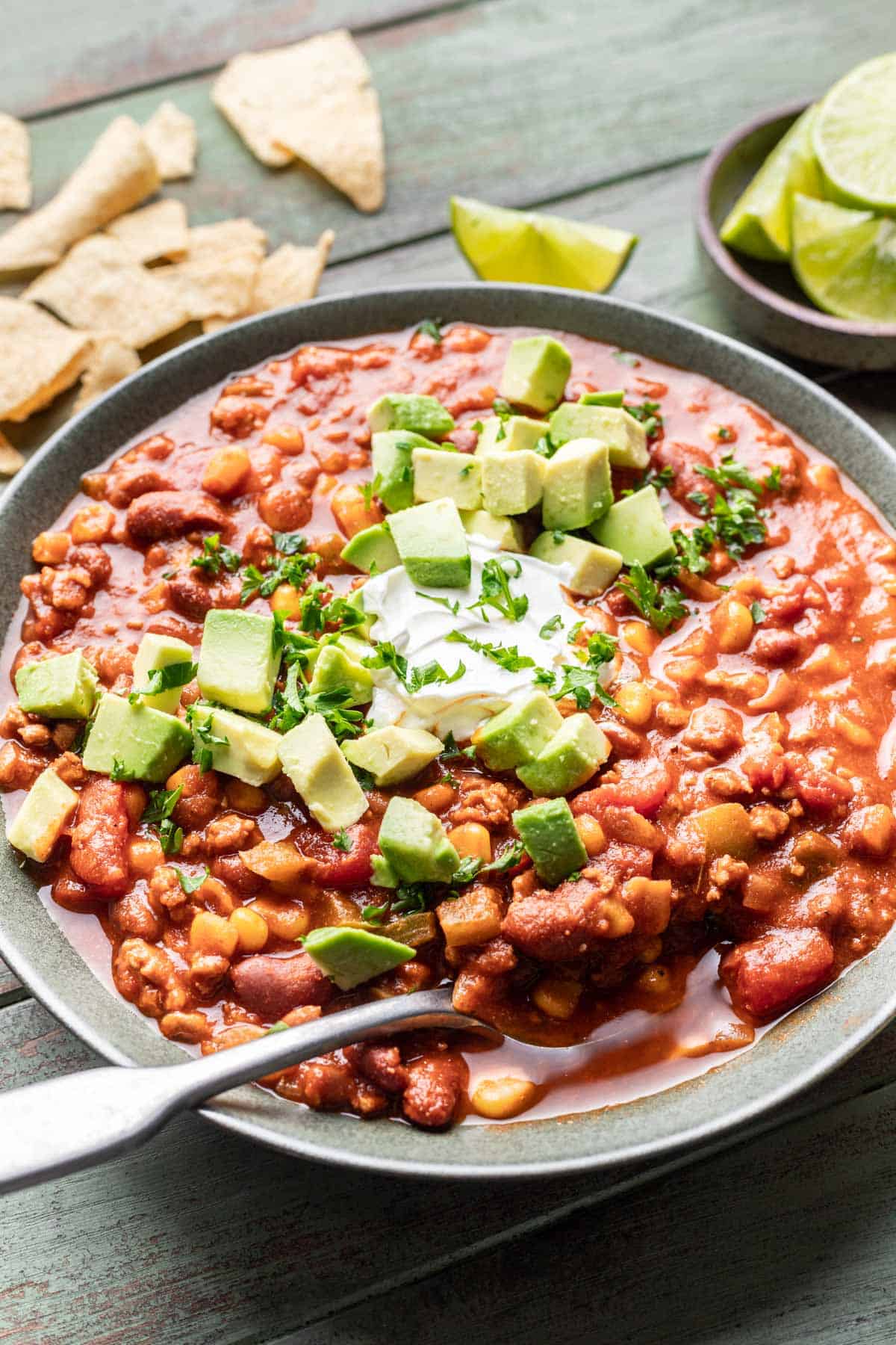 Dutch oven chili in a bowl with a spoon and crushed tortilla chips.