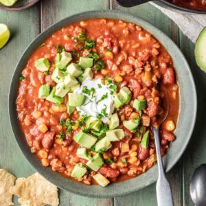 Dutch oven chili in a green bowl with a spoon.