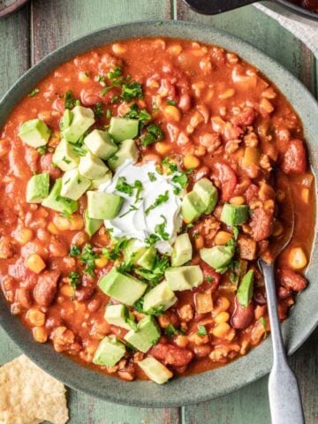 Dutch oven chili in a green bowl with a spoon.